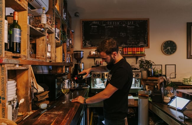 Avi pouring a glass of wine at Six Ounces, Christchurch.