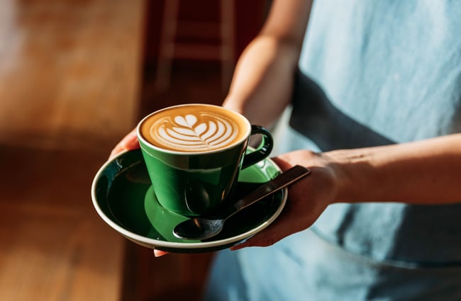 Barista holding a cup of coffee at Sketchbook Coffee.
