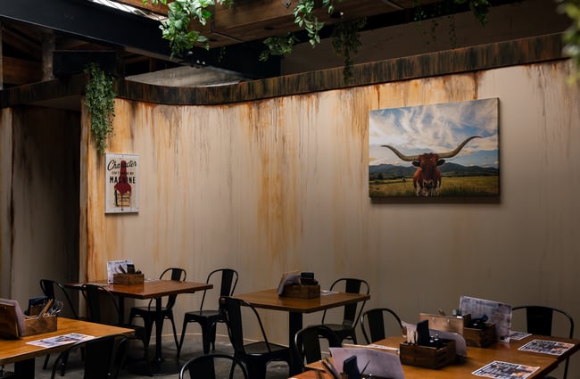 Dining chairs and tables next to a wall painted to look like it's rusty.
