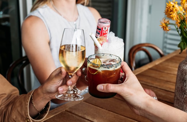 Three customers holding up their drinks and doing a cheers at Sofi.