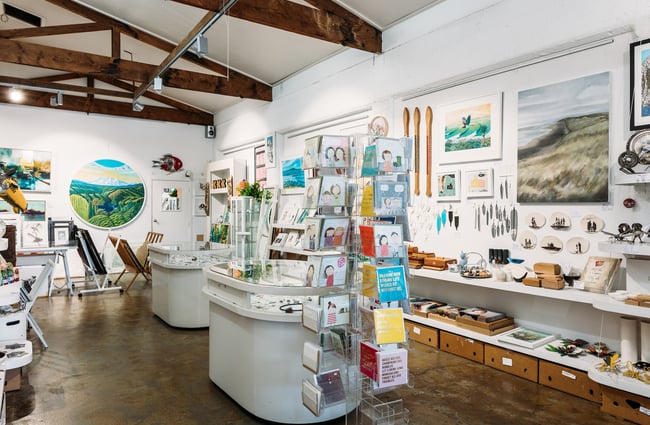 Interior of Soul Gallery in Hamilton with exposed wooden trusses, art on the wall and on central displays.