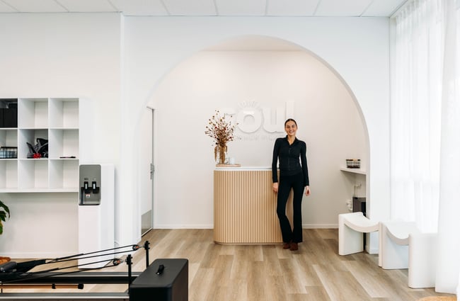 Instructor standing by the front desk in the Pilates studio.