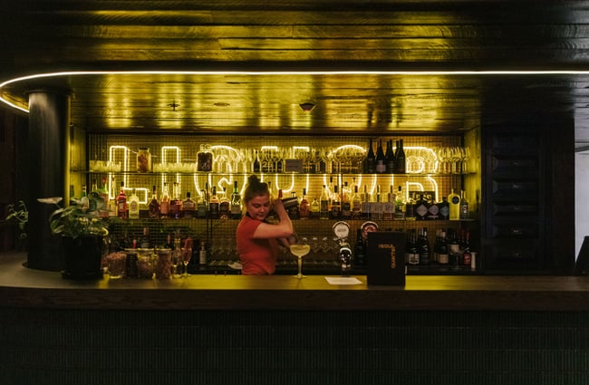 Woman making cocktail behind the bar.