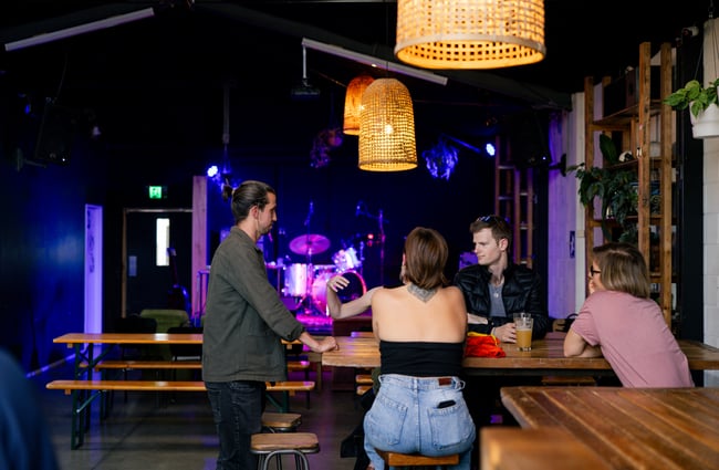 Table of customers with live music set up in the background at Space Academy.