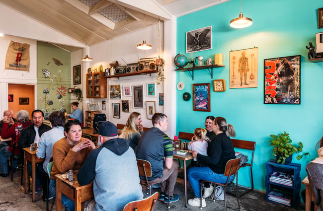 People sitting at tables inside Space Cadet, Hamilton.
