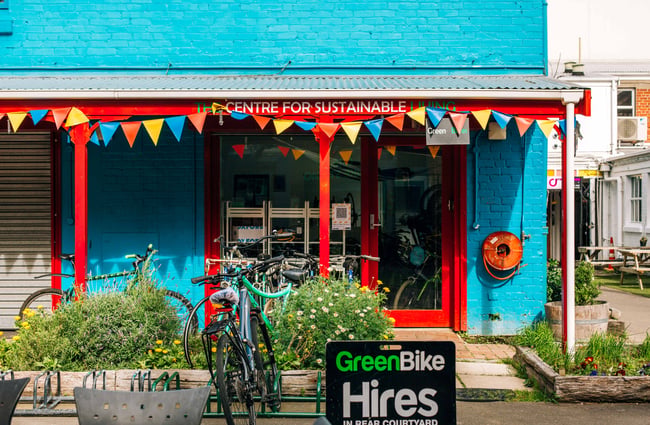 A blue building with red supporting beams, and colourful bunting.