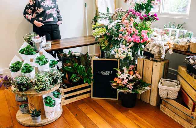 A corner filled with lots of flowers and a sign.