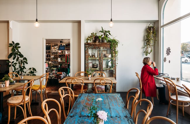 A woman in red sipping a drink at a window seat inside Squirrel cafe.