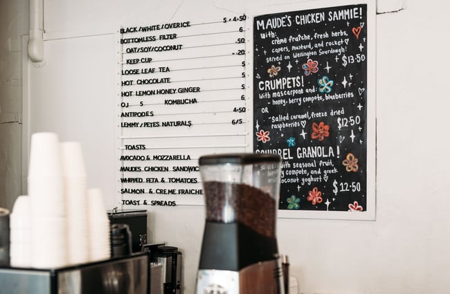A close up of a typed and hand drawn menu behind a cafe counter.