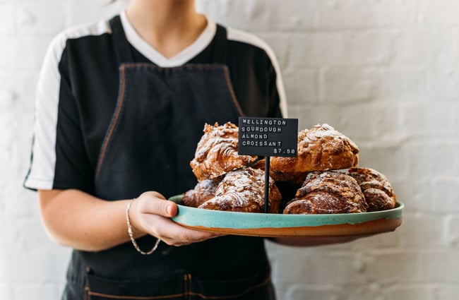 A staff member holding a plate of croissants.