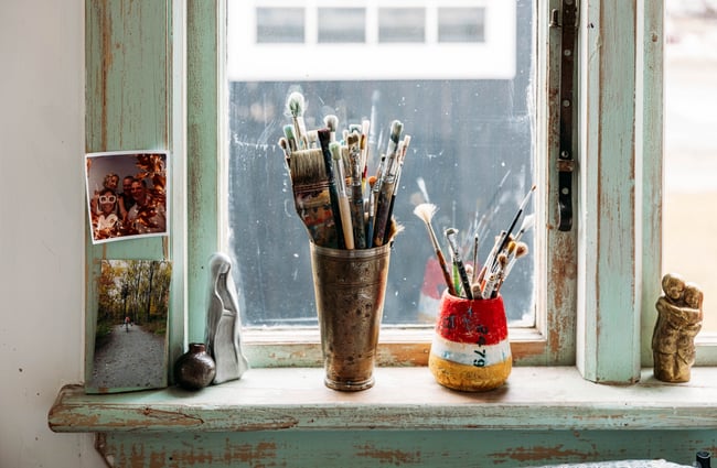 Paint brushes in jars on a window sill.