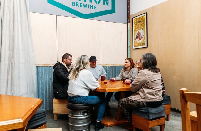A group of people sitting at a table inside a brewery.
