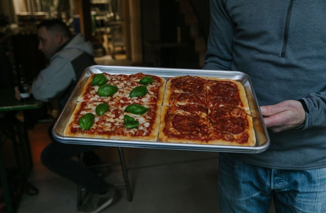 Person holding a pizza on a tray from Steamer Basin, Dunedin.