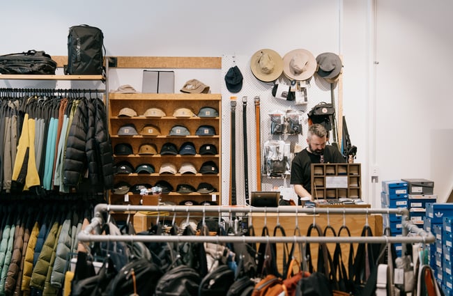 Man behind counter with racks of clothing and shelves of accessories surrounding him at Stencil in Christchurch