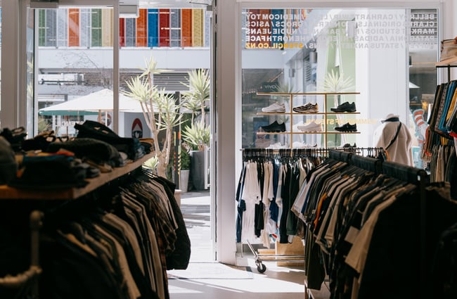 Racks of t-shirts with a view of laneway through the window from inside Stencil Store in Christchurch