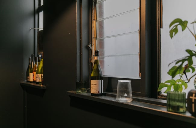 Wine bottles, a potted plant and other decorations along a windowsill.