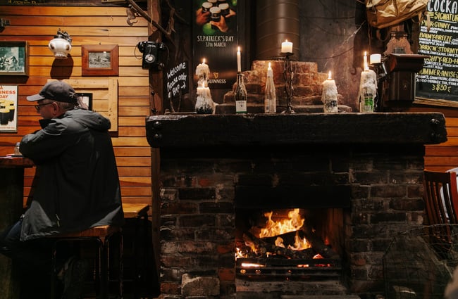 Stone fireplace with cosy fire roaring and lots of candles on the ledge above.