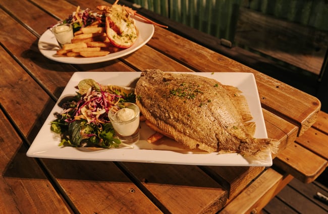 Whole fish crumbed with chips on a table at Strawberry Tree.