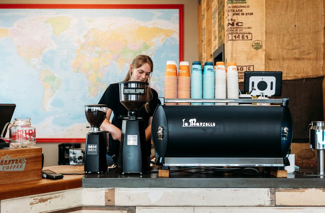 Barista behind coffee machine making a coffee at Sublime Coffee Roasters.