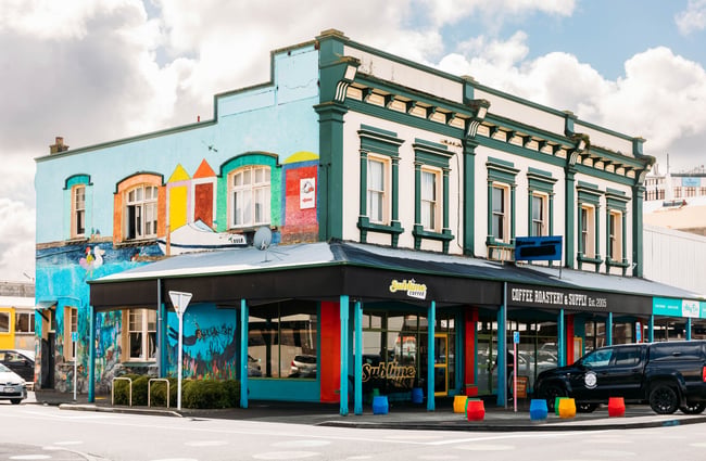 Colourful building exterior of Sublime Coffee Roasters with cars parked outside.