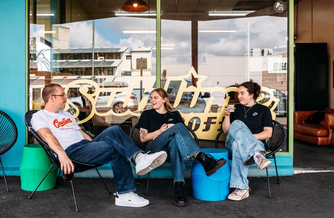 A group of customers are sitting outside, drinking their coffees from Sublime Coffee Roasters.