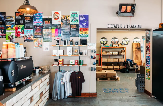 Merchandise is hanging up on the wall in the foreground and in the background there's a doorway through to a seating area at Sublime Coffee Roasters.