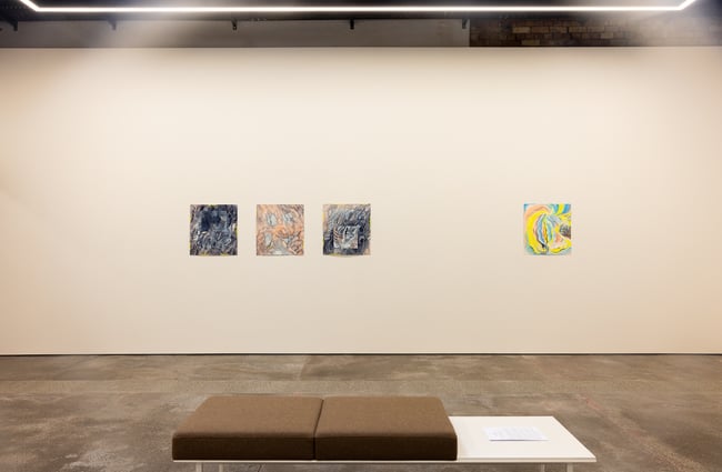 Four works of art on display on a white wall.