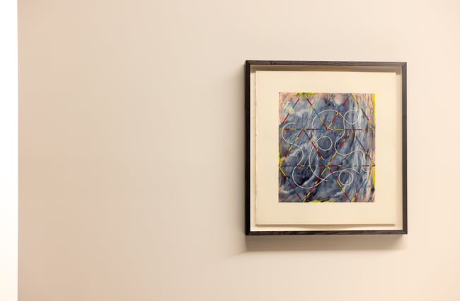 A close up of small framed work of art on a wall.