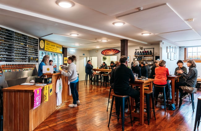 People dining at high tables inside a light and bright bar.