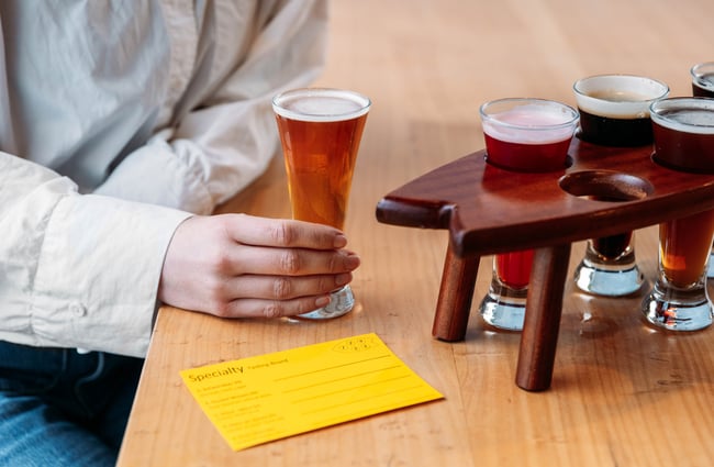 A hand holding a half pint of beer.