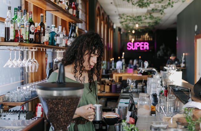 Woman making drinks behind the bar.