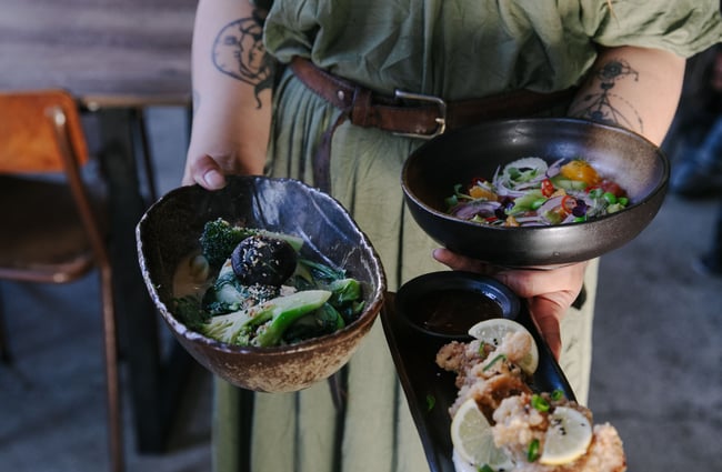 Waitress holding three dishes from SUPER.