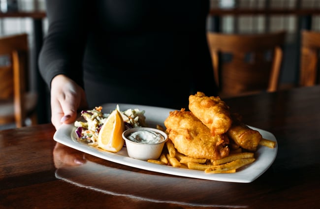 A close up of fish and chips on a white plate.