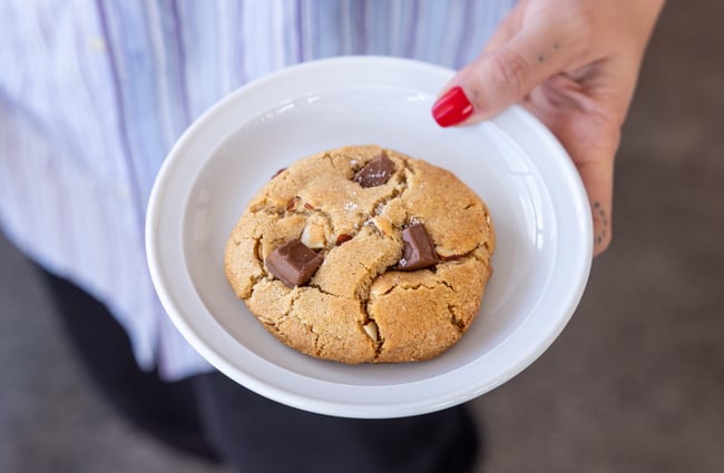 A customer holds a cookie on a plate at Supreme Supreme.