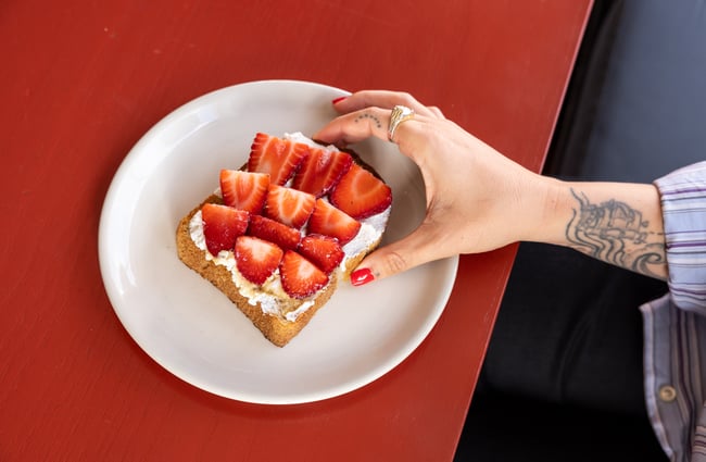 Customer picks up a piece of Strawberry toast at Supreme Supreme.