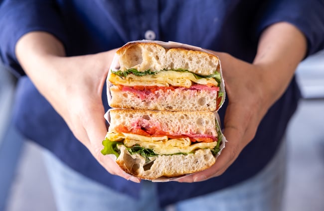 A customer holds a stack of focaccia sandwiches at Supreme Supreme.