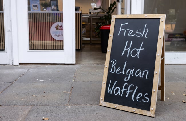 Blackboard signage sits outside front door of Sweet As Waffles.