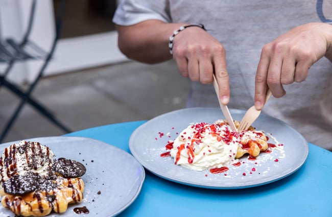 A customer cuts into a plate of waffles at Sweet As Waffles.