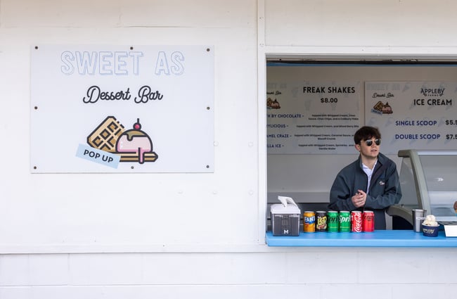 Staff member stands behind the front counter of a dessert bar by Sweet As Waffles.