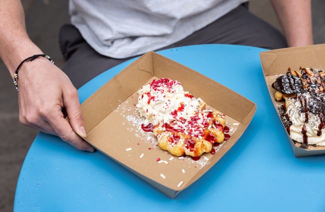 Customer hold two different waffle options at a table at Sweet As Waffles.
