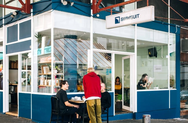 Exterior blue cafe with patrons eating outside.