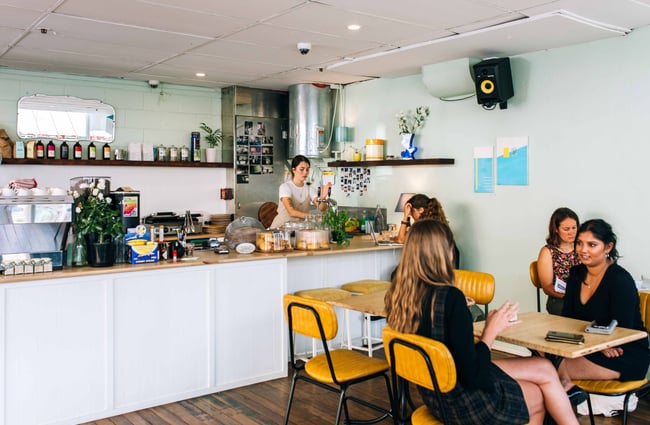 People seated at yellow chairs near a long white counter.
