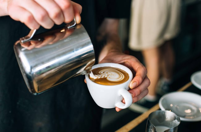 Woman pouring a flat white.