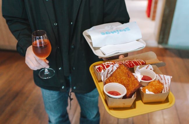 Person carrying a plastic yellow tray with Swings food on it.