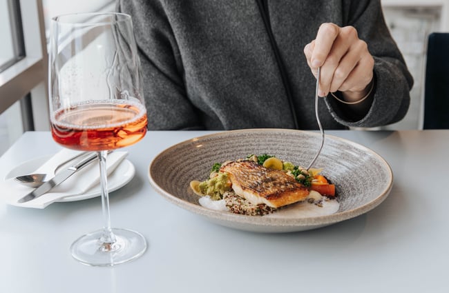 A plate of food and glass of rose.