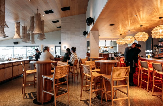 Customers sitting at high tables and chairs inside a restaurant.