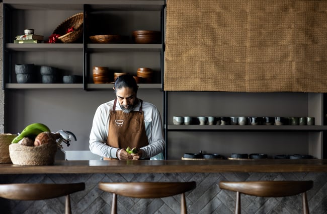 A male chef working behind the counter inside an open kitchen.