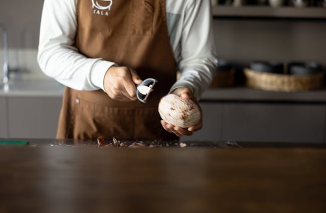Hands peeling a large root vegetable.