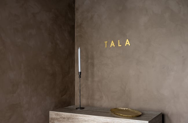 A gold 'Tala' sign on a wall.