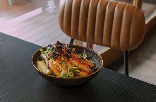 A bowl of Japanese food on a black table.